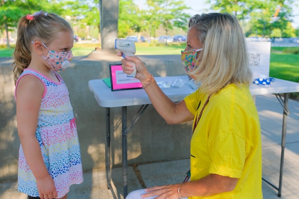 A student gets her temperature checked before being allowed back at school.