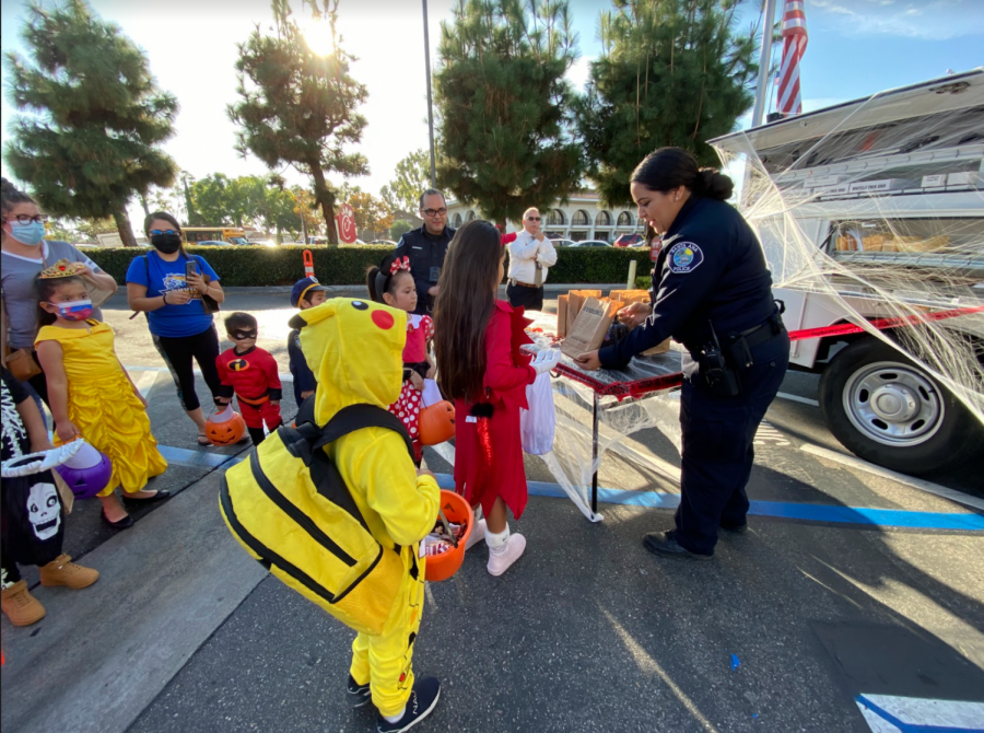 Lorena Cordova, a crime scene investigator, hands out candy to trick-or-treaters at the Santa Ana Police Department’s Trunk-or-Treat event on Thursday Oct. 21, 2021 at Chick-fil-A on Bristol and MacArthur Street.