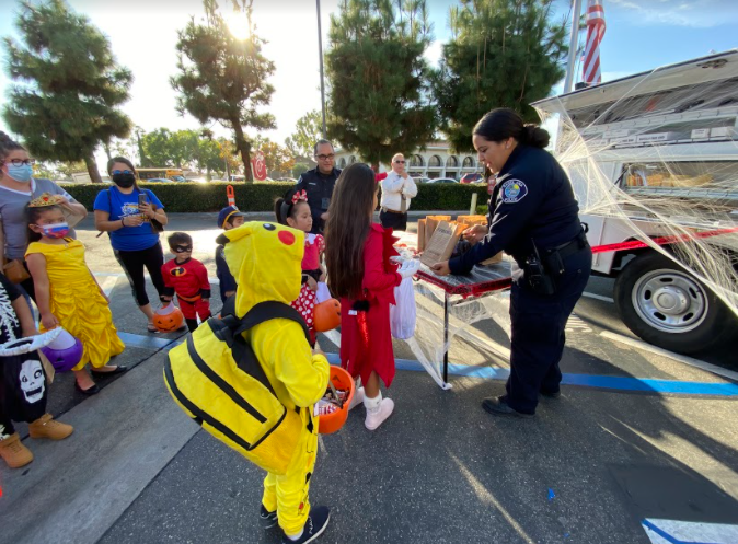 Lorena Cordova, a crime scene investigator, hands out candy to trick-or-treaters at the Santa Ana Police Department’s Trunk-or-Treat event on Thursday Oct. 21, 2021 at Chick-fil-A on Bristol and McArthur St.