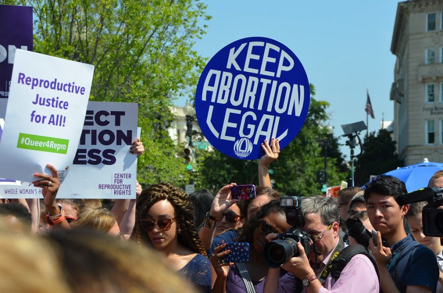 Protesters at a womens rally hold signs to protect womens reproductive rights. 