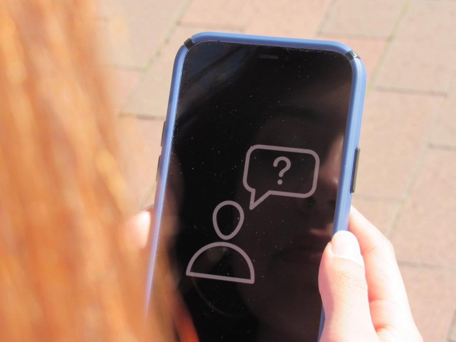 A teen looks at a phone displaying an icon of someone asking a question.