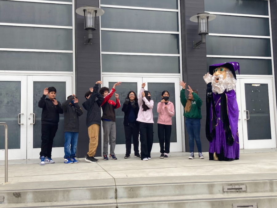 Seventh-graders pose in front of the big SAC gym with Walter the Wizard.