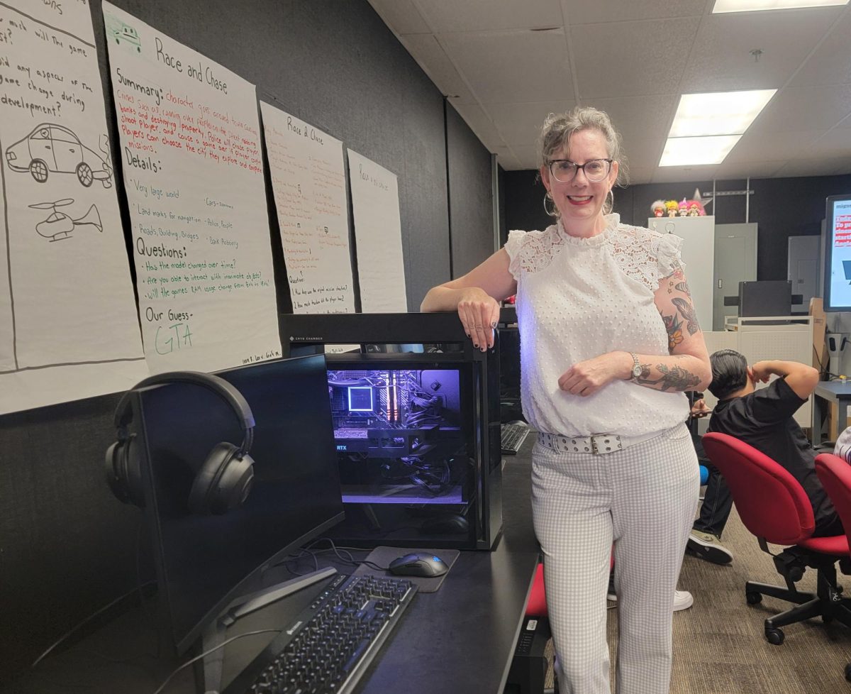 Esports teacher Laura Compton stands beside one of the new gaming computers in Room B-15. The upgraded lab gives students more space and better technology to practice competitive gaming, design levels in Unreal Engine, and work toward professional certifications.