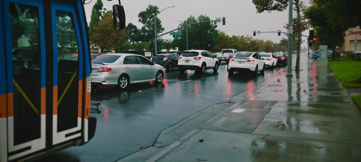 An OCTA bus finishes dropping off students on 17th and Bristol, and heads off on Tuesday, Oct. 14, 2025. It is raining hard, yet traffic near Santa Ana College is slow as always.